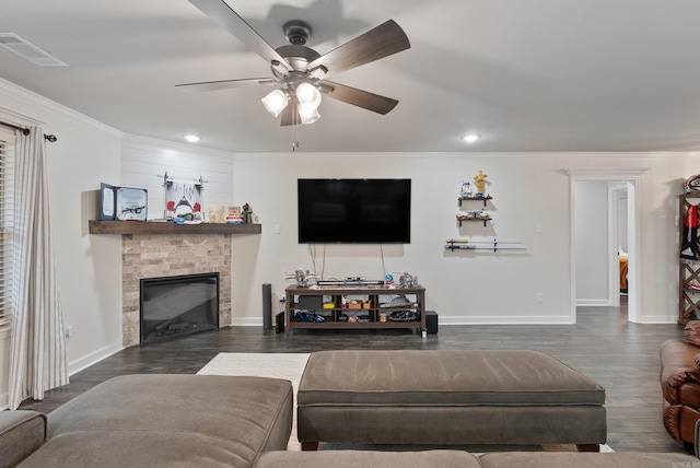 living room with dark hardwood / wood-style flooring, a stone fireplace, ornamental molding, and ceiling fan