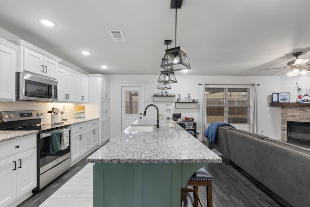 kitchen featuring hanging light fixtures, a center island with sink, white cabinets, and appliances with stainless steel finishes