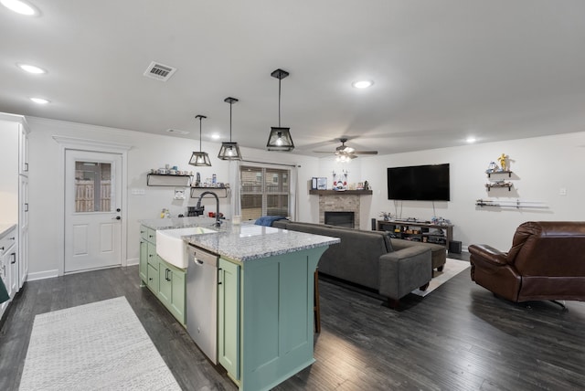 kitchen featuring decorative light fixtures, an island with sink, dishwasher, sink, and green cabinetry