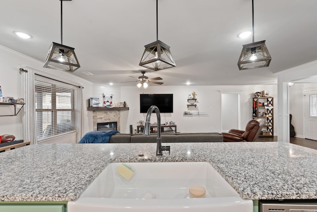 kitchen with sink, light stone counters, and decorative light fixtures