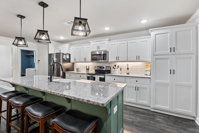 kitchen with pendant lighting, a kitchen island with sink, white cabinets, and appliances with stainless steel finishes