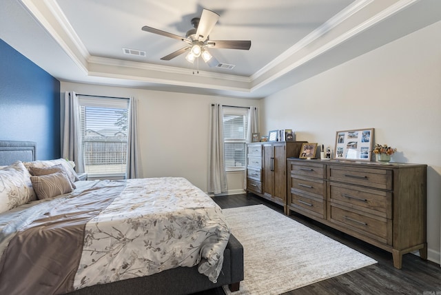 bedroom featuring crown molding, dark hardwood / wood-style floors, ceiling fan, and a tray ceiling