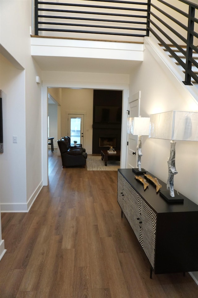 corridor with a towering ceiling and dark hardwood / wood-style flooring