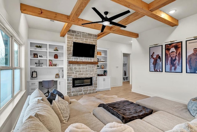 living room with beamed ceiling, ceiling fan, a stone fireplace, and light hardwood / wood-style floors