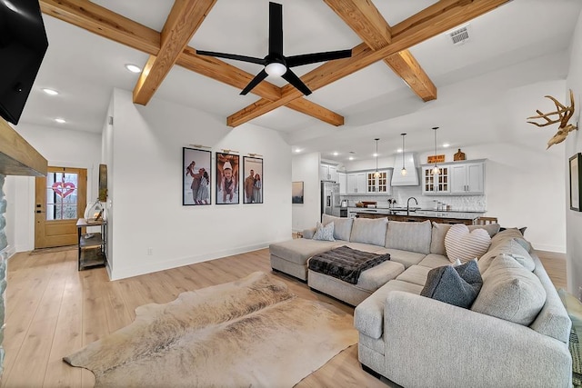 living room featuring beamed ceiling, coffered ceiling, and light wood-type flooring