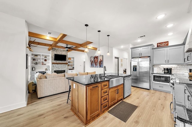 kitchen with sink, ceiling fan, appliances with stainless steel finishes, a center island with sink, and decorative light fixtures