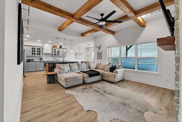 living room with beamed ceiling, coffered ceiling, and light hardwood / wood-style floors