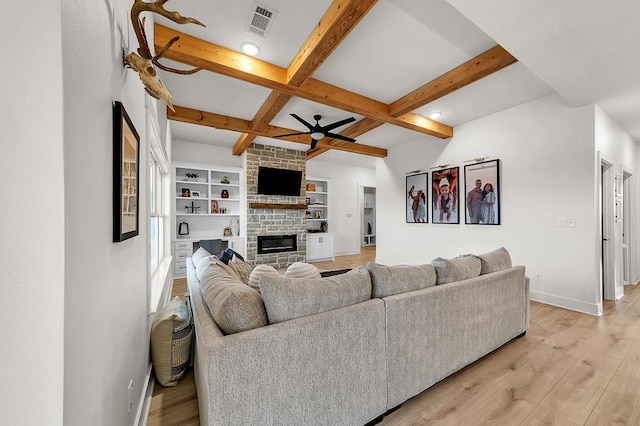 living room with beamed ceiling, a fireplace, coffered ceiling, and light wood-type flooring