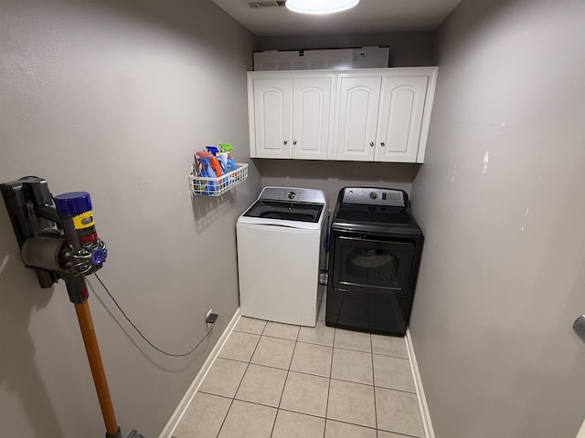 washroom featuring separate washer and dryer, light tile patterned floors, and cabinets