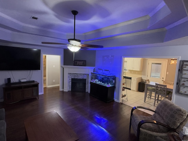 living room with a tray ceiling, a fireplace, and ornamental molding