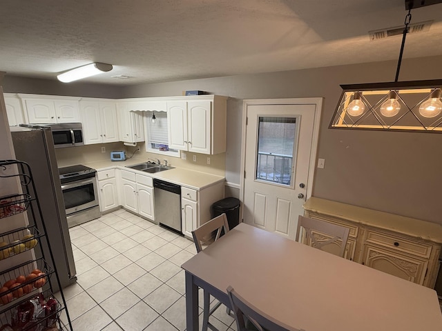 kitchen with white cabinetry, decorative light fixtures, stainless steel appliances, and light tile patterned flooring