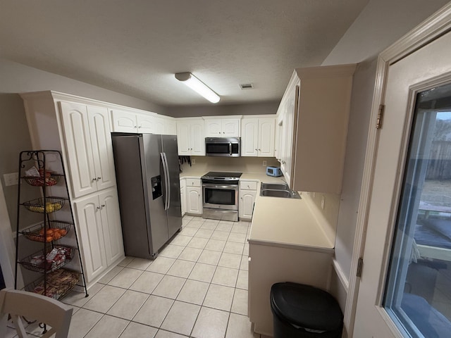 kitchen with white cabinetry, sink, light tile patterned floors, and stainless steel appliances