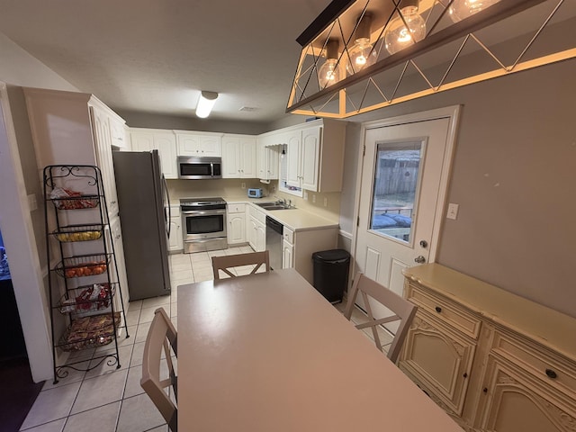 kitchen with sink, light tile patterned floors, white cabinets, and appliances with stainless steel finishes