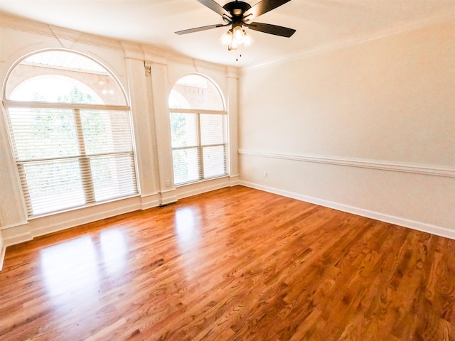 empty room featuring hardwood / wood-style floors, a wealth of natural light, ornamental molding, and ceiling fan