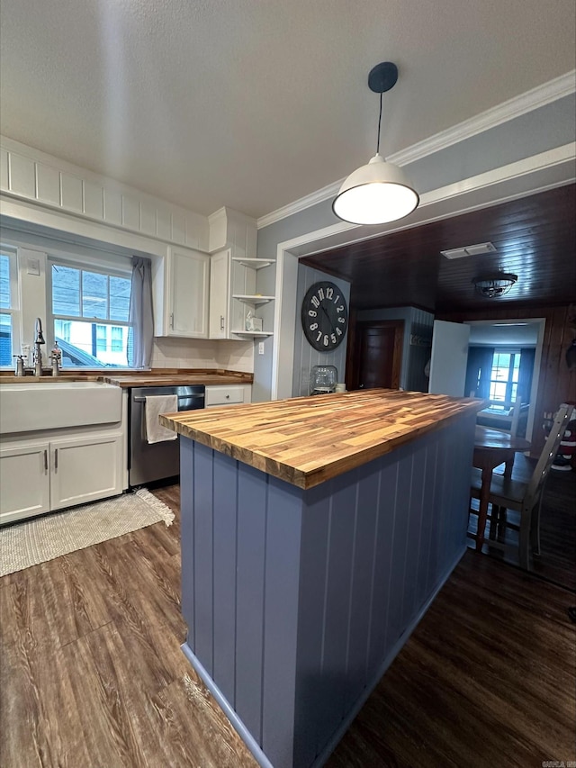 kitchen featuring butcher block countertops, sink, white cabinetry, decorative light fixtures, and stainless steel dishwasher