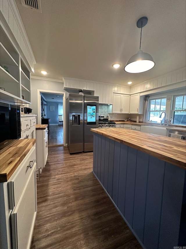 kitchen featuring stainless steel appliances, white cabinetry, butcher block counters, and decorative light fixtures