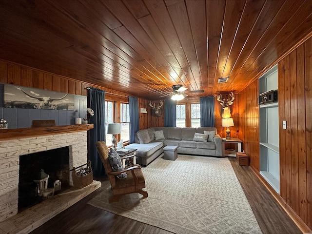 living room with wood-type flooring, a brick fireplace, wooden ceiling, and wooden walls