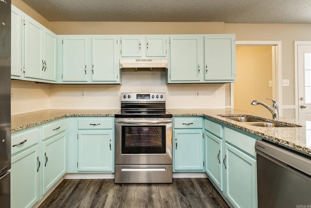 kitchen featuring appliances with stainless steel finishes, dark hardwood / wood-style floors, sink, light stone counters, and a textured ceiling