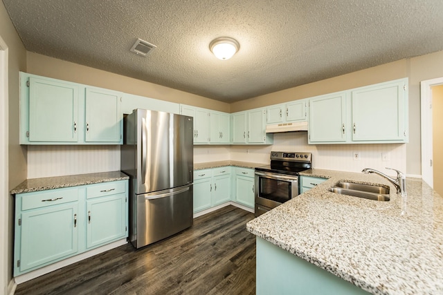 kitchen featuring dark hardwood / wood-style floors, sink, light stone counters, stainless steel appliances, and a textured ceiling