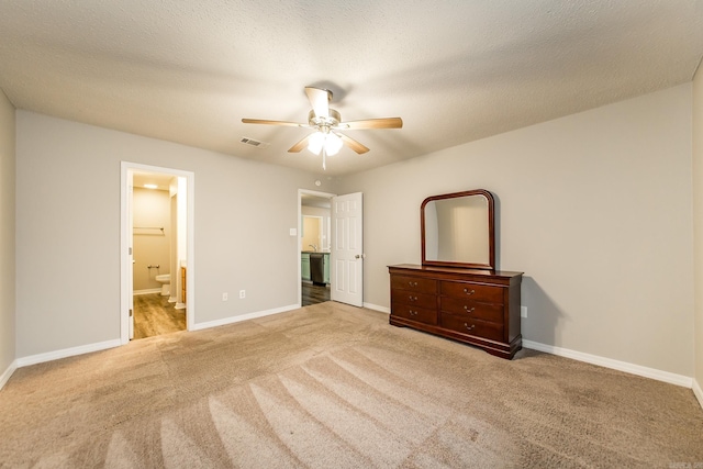 unfurnished bedroom featuring ceiling fan, ensuite bathroom, carpet floors, and a textured ceiling