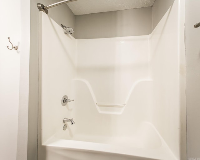 bathroom with tub / shower combination and a textured ceiling