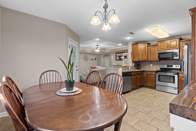 tiled dining space featuring sink and ceiling fan with notable chandelier