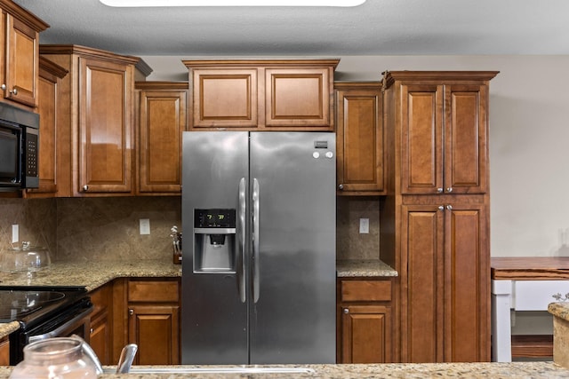 kitchen with light stone counters, stainless steel appliances, and tasteful backsplash