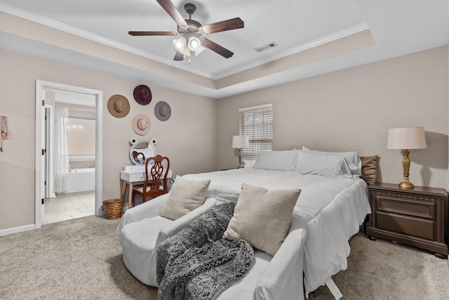 carpeted bedroom featuring ornamental molding, ensuite bathroom, and a tray ceiling