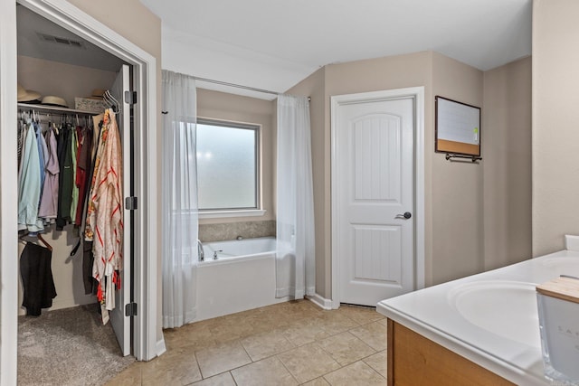 bathroom featuring vanity, a tub to relax in, and tile patterned flooring