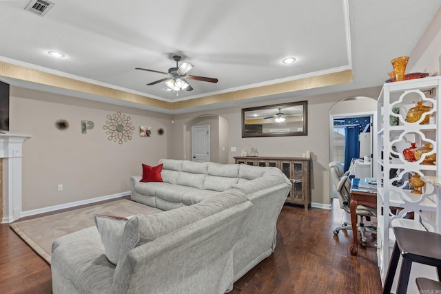 living room featuring a tray ceiling, crown molding, dark wood-type flooring, and ceiling fan