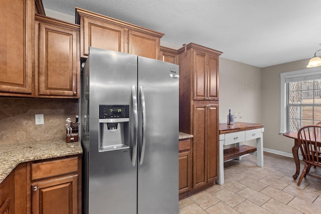 kitchen featuring tasteful backsplash, light stone counters, and stainless steel fridge with ice dispenser