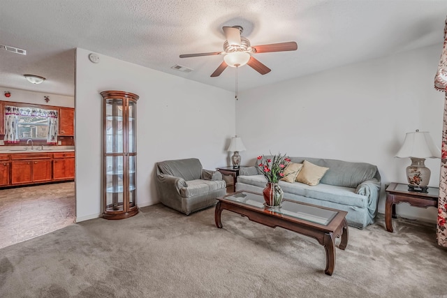 living room featuring ceiling fan, sink, light colored carpet, and a textured ceiling