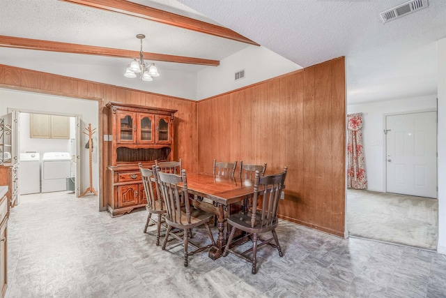 dining room with an inviting chandelier, wood walls, vaulted ceiling with beams, washing machine and dryer, and a textured ceiling