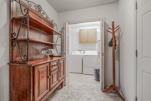 laundry room featuring cabinets, washing machine and clothes dryer, and a textured ceiling