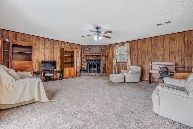 living room with ceiling fan, a fireplace, a textured ceiling, and carpet