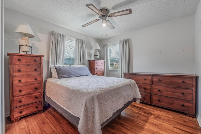 bedroom with dark hardwood / wood-style flooring, ceiling fan, and a textured ceiling