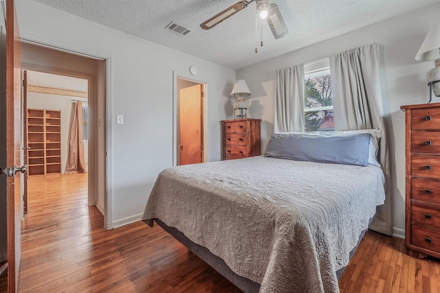 bedroom with ceiling fan, hardwood / wood-style flooring, and a textured ceiling