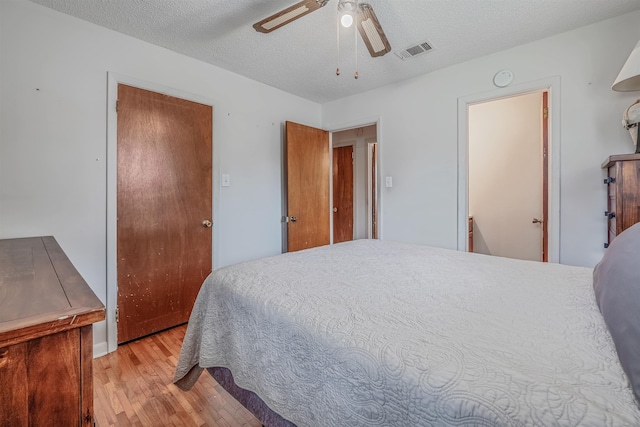 bedroom with ceiling fan, a textured ceiling, and light wood-type flooring