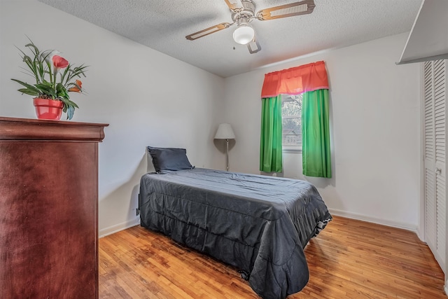 bedroom with ceiling fan, light hardwood / wood-style flooring, and a textured ceiling