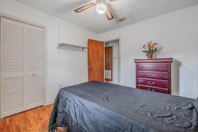 bedroom with a closet, ceiling fan, a textured ceiling, and light hardwood / wood-style flooring