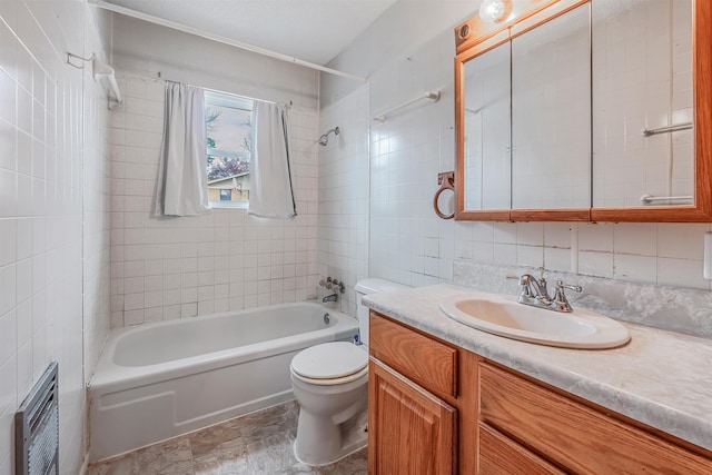 full bathroom with vanity, toilet, tiled shower / bath combo, and tile walls