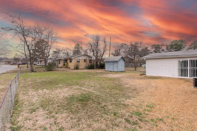 yard at dusk featuring a storage unit