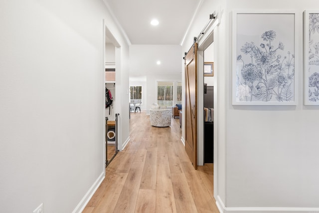 hallway with a barn door and light hardwood / wood-style flooring