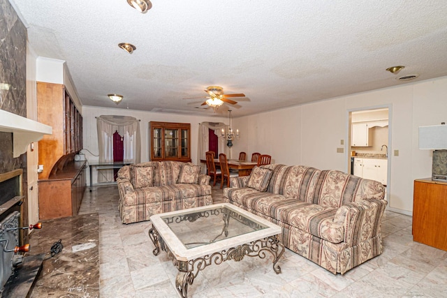 living room featuring sink, ceiling fan with notable chandelier, and a textured ceiling