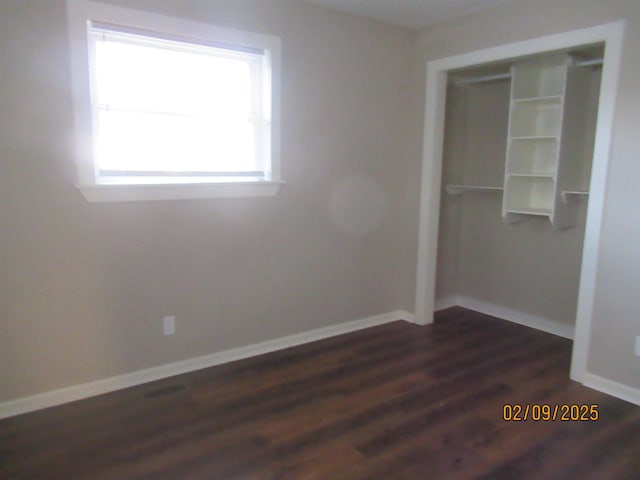 unfurnished bedroom with dark hardwood / wood-style flooring and a closet