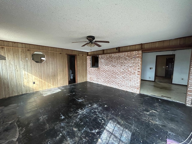 unfurnished living room featuring wooden walls and a textured ceiling