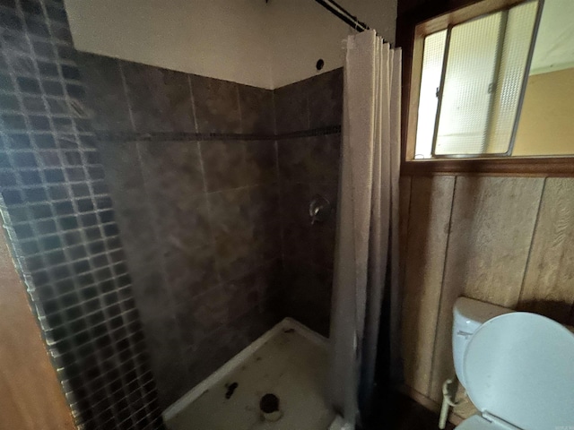 bathroom featuring walk in shower, wooden walls, and toilet