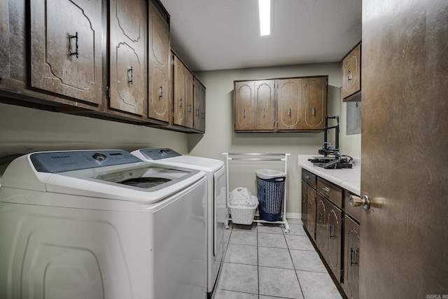 washroom with light tile patterned floors, washing machine and dryer, and cabinets