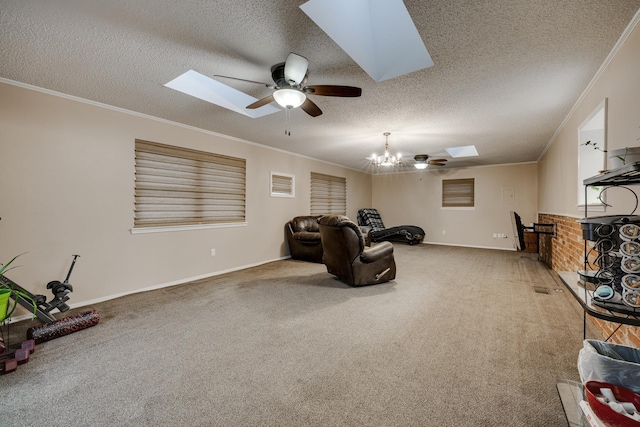 carpeted living room with ceiling fan with notable chandelier, a skylight, ornamental molding, and a textured ceiling