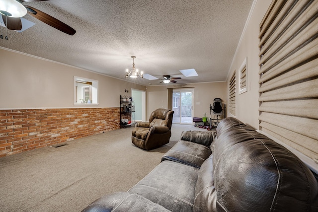 living room with ceiling fan with notable chandelier, a skylight, ornamental molding, carpet, and a textured ceiling